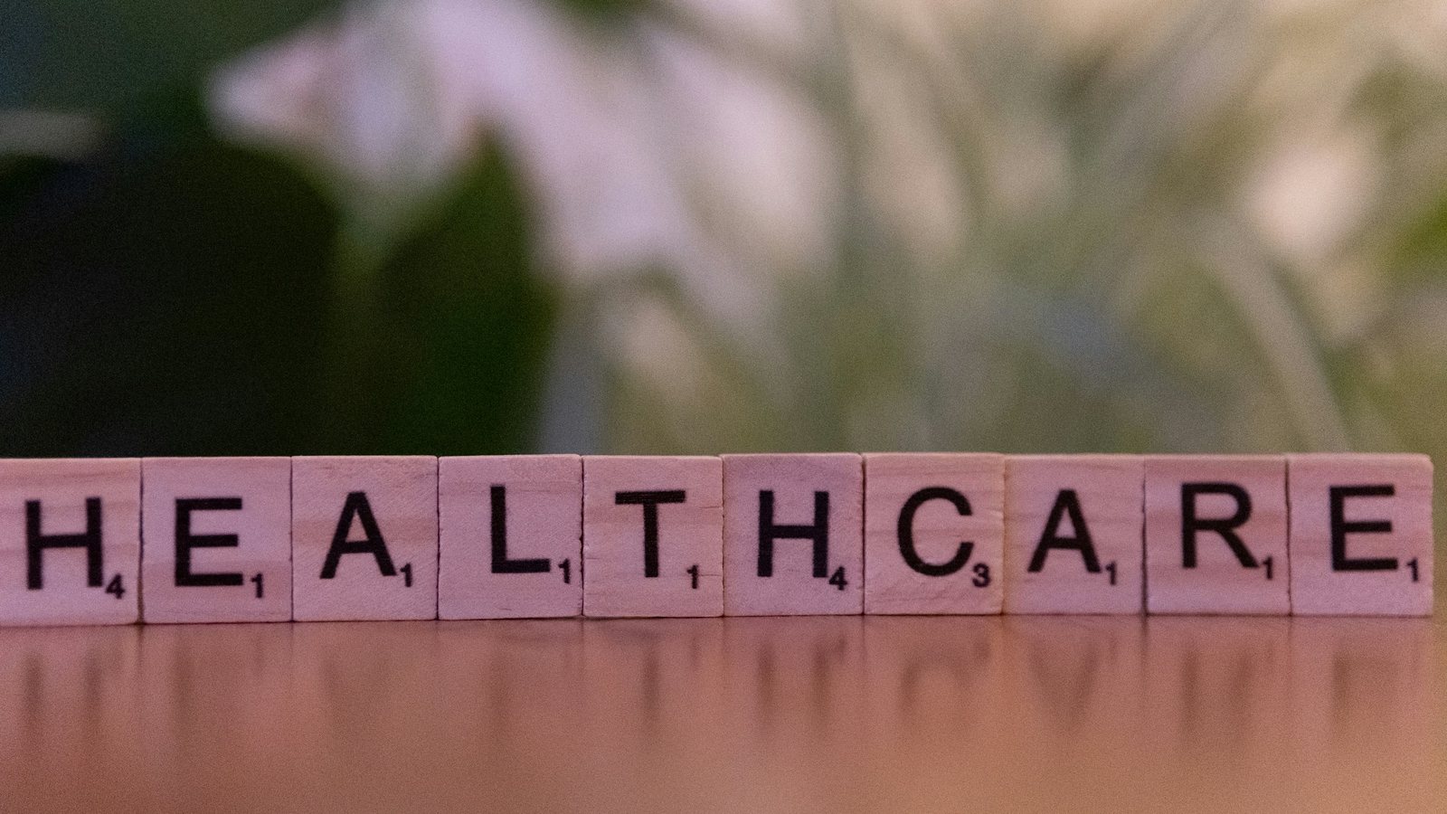 Letter tiles spelling HEALTHCARE on a wooden table.