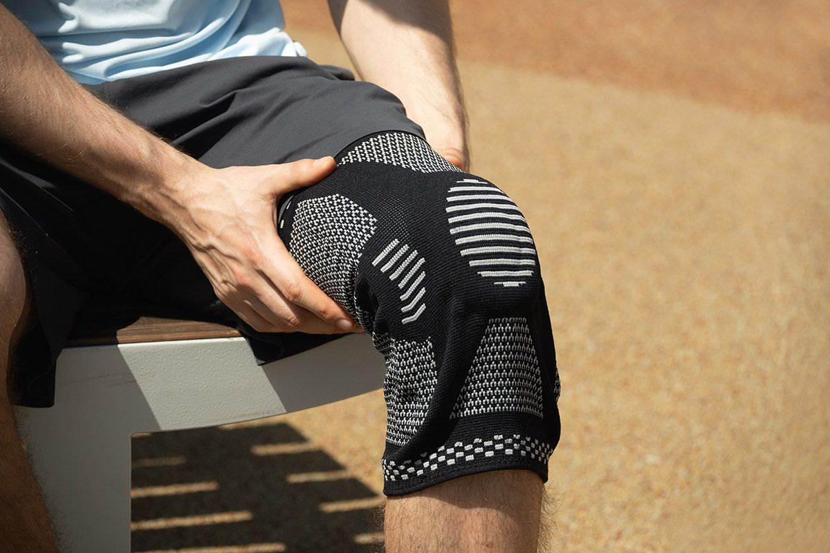 Knee support brace on male legs outdoors in summer.