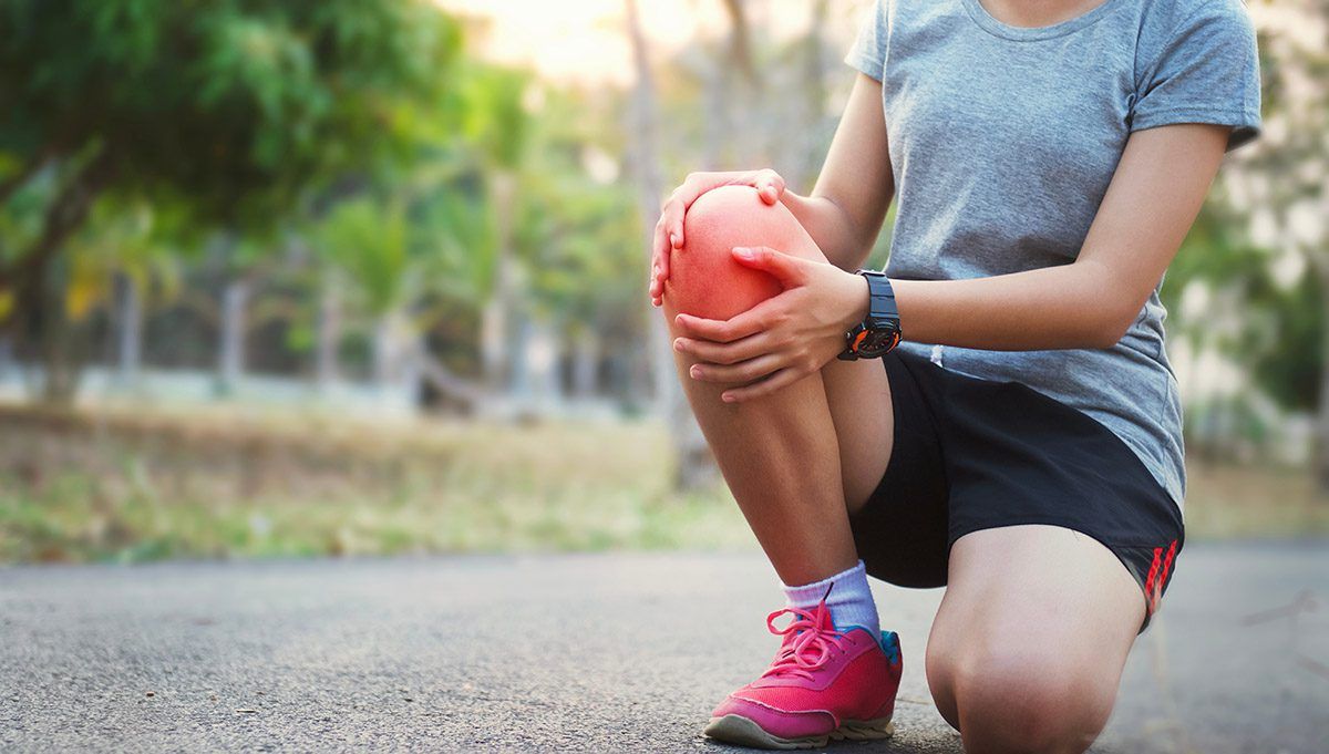 Young woman holding her knee after an ACL tear.